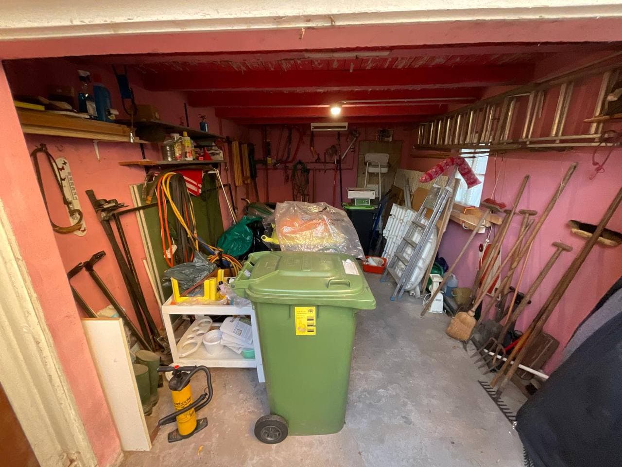 Volle Garage mit Werkzeug, Regalen und Mülltonne vor der Räumung
