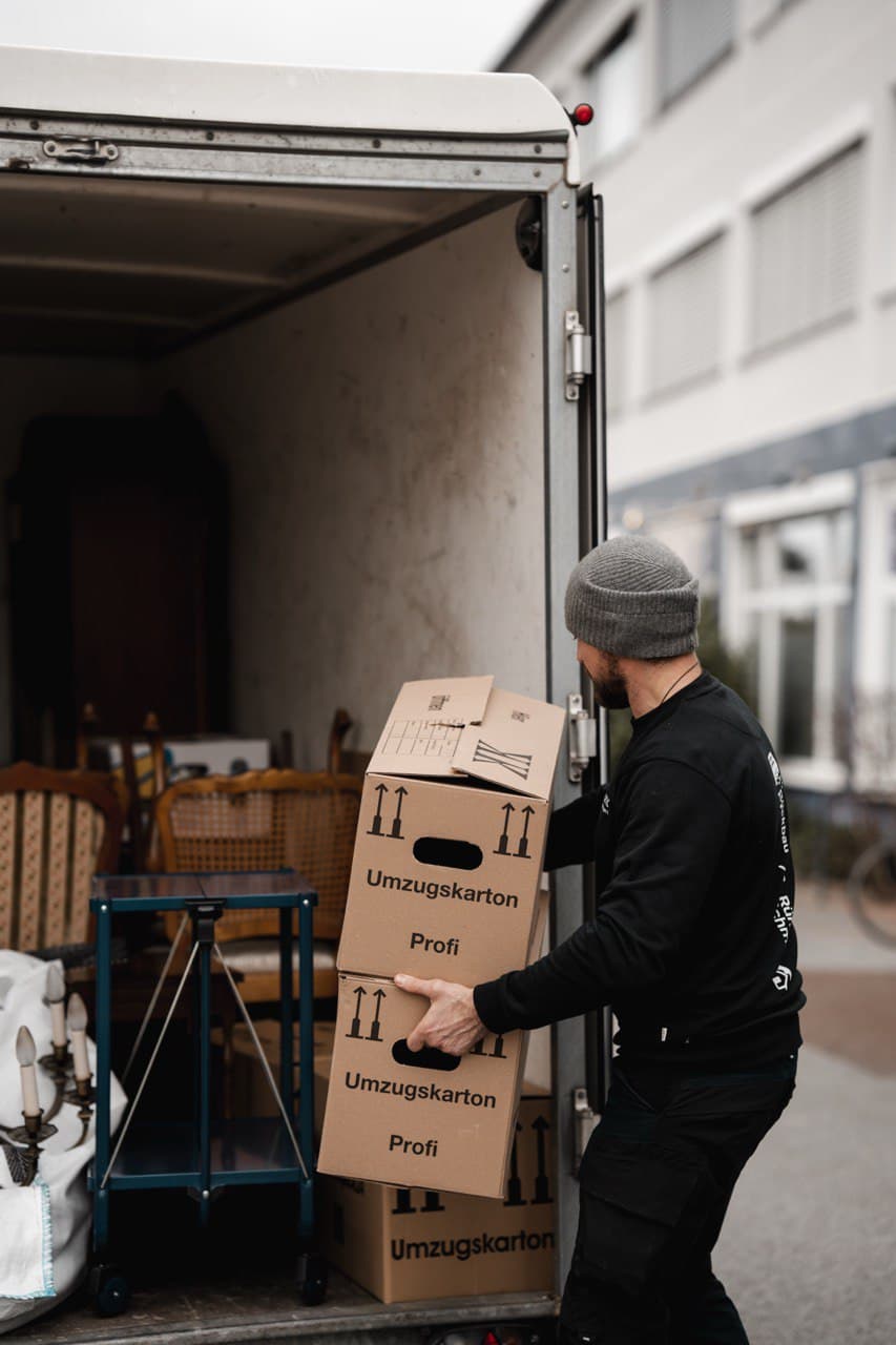 Mitarbeiter trägt Kartons zum Transporter